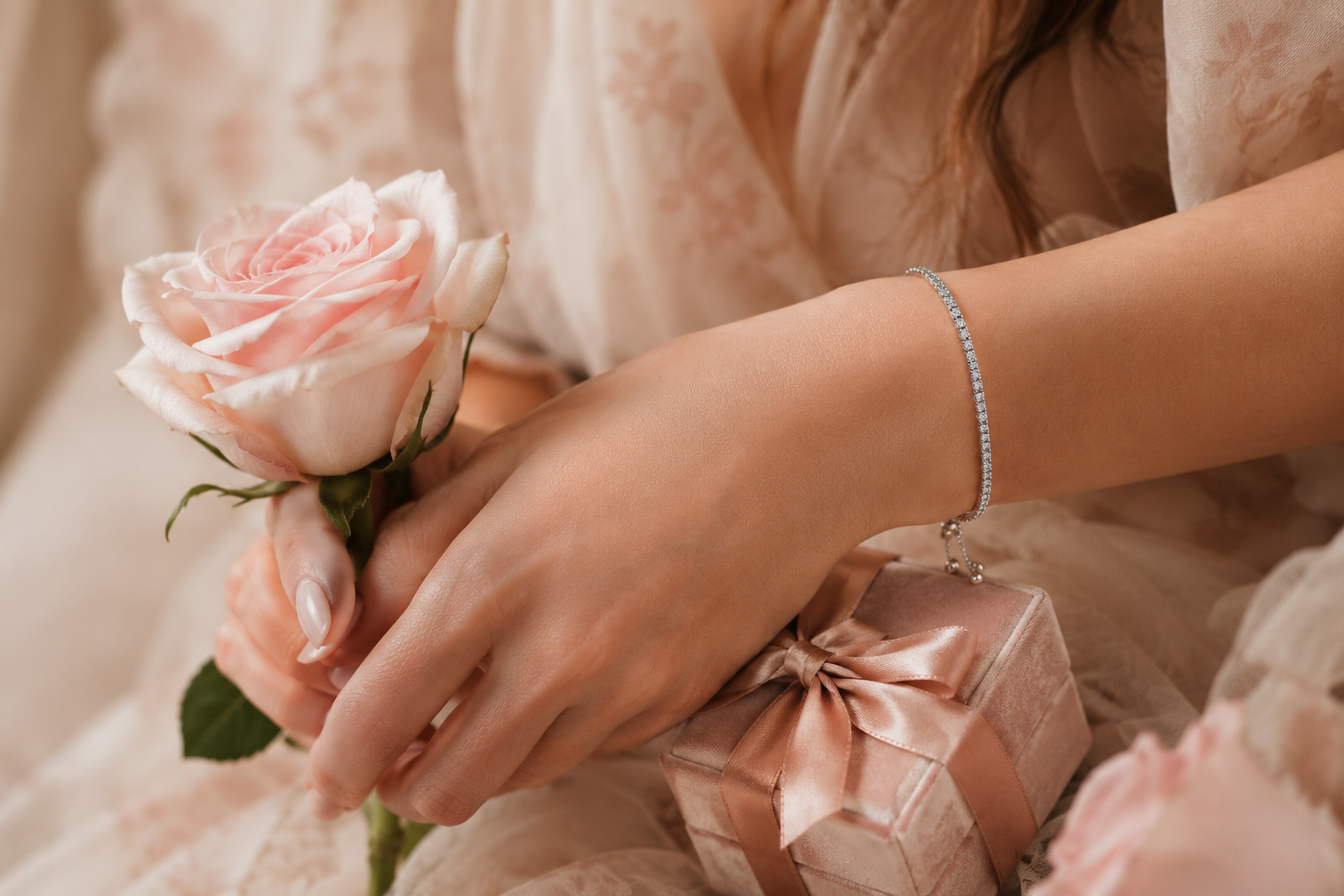 Woman wearing a delicate moissanite bracelet with a pink rose and gift box