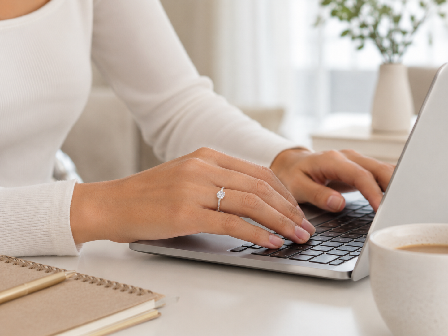 Woman wearing a moissanite ring while working on a laptop