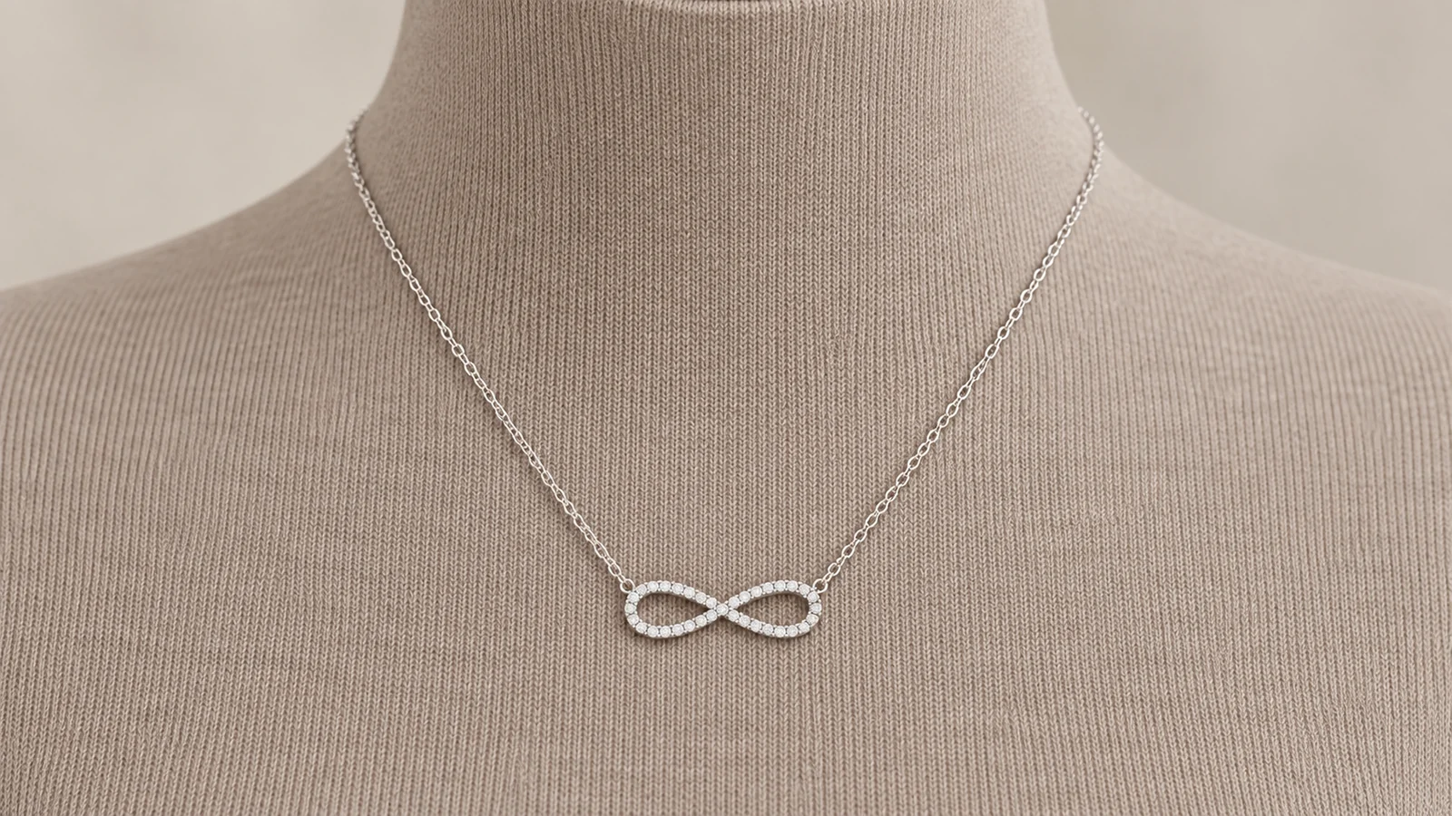 Infinity pavé necklace centered on a taupe knit display
