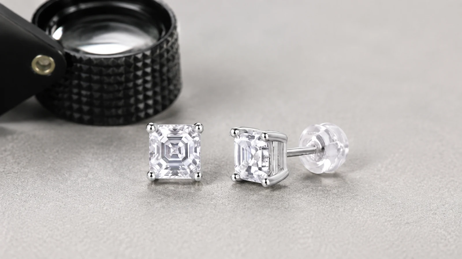 MS0258 square cut moissanite stud earrings beside a jeweler's loupe
