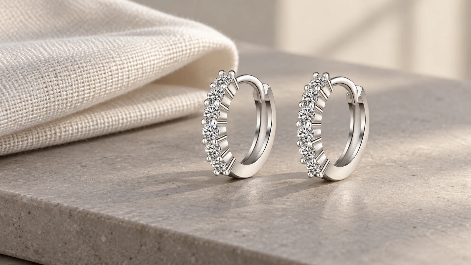 Round pavé huggie hoop earrings on warm gray stone
