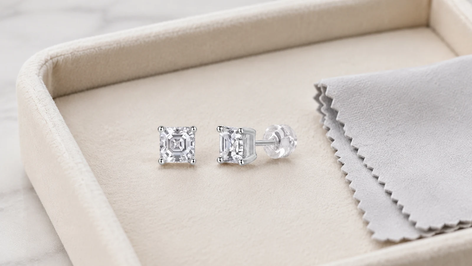 MS0258 moissanite stud earrings stored in a lined tray beside a soft cloth