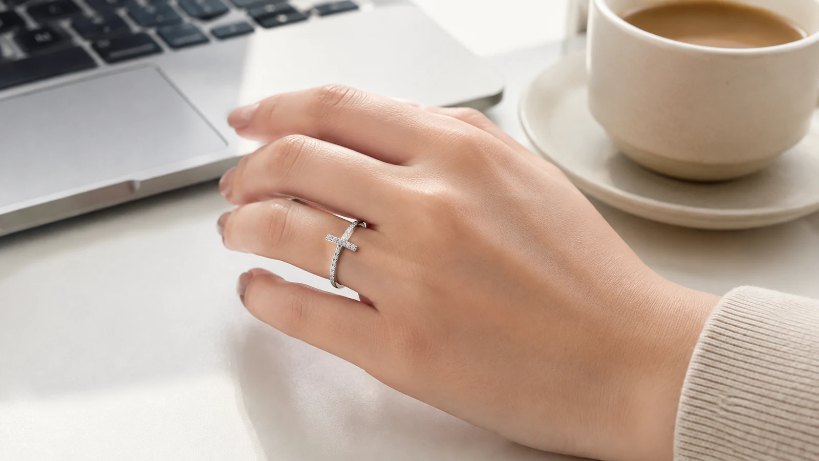 MS0159 X cross ring worn on a hand beside a laptop and coffee cup